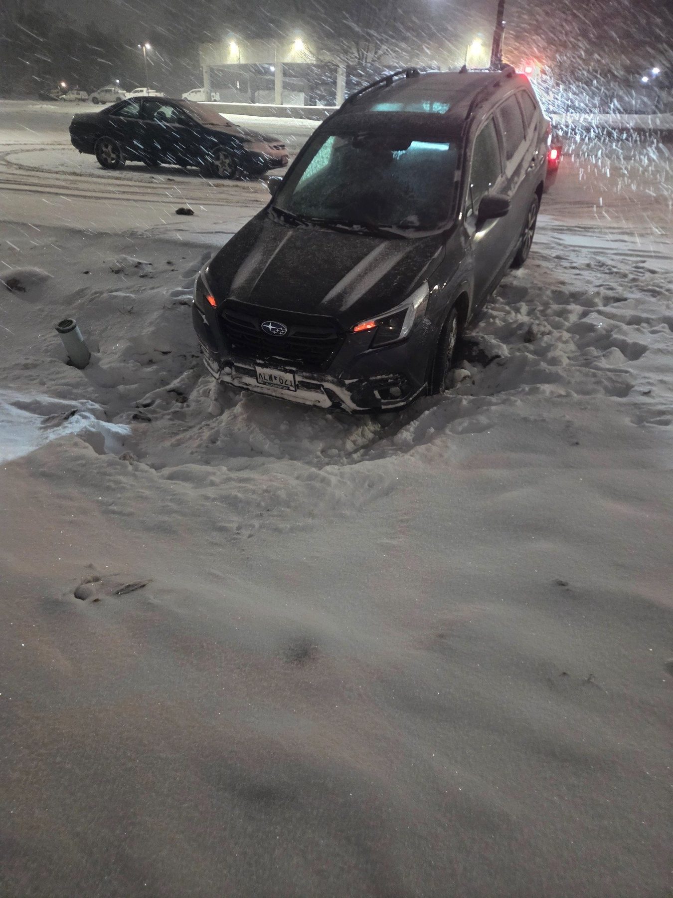 SUV stuck in deep snow in a parking lot at night