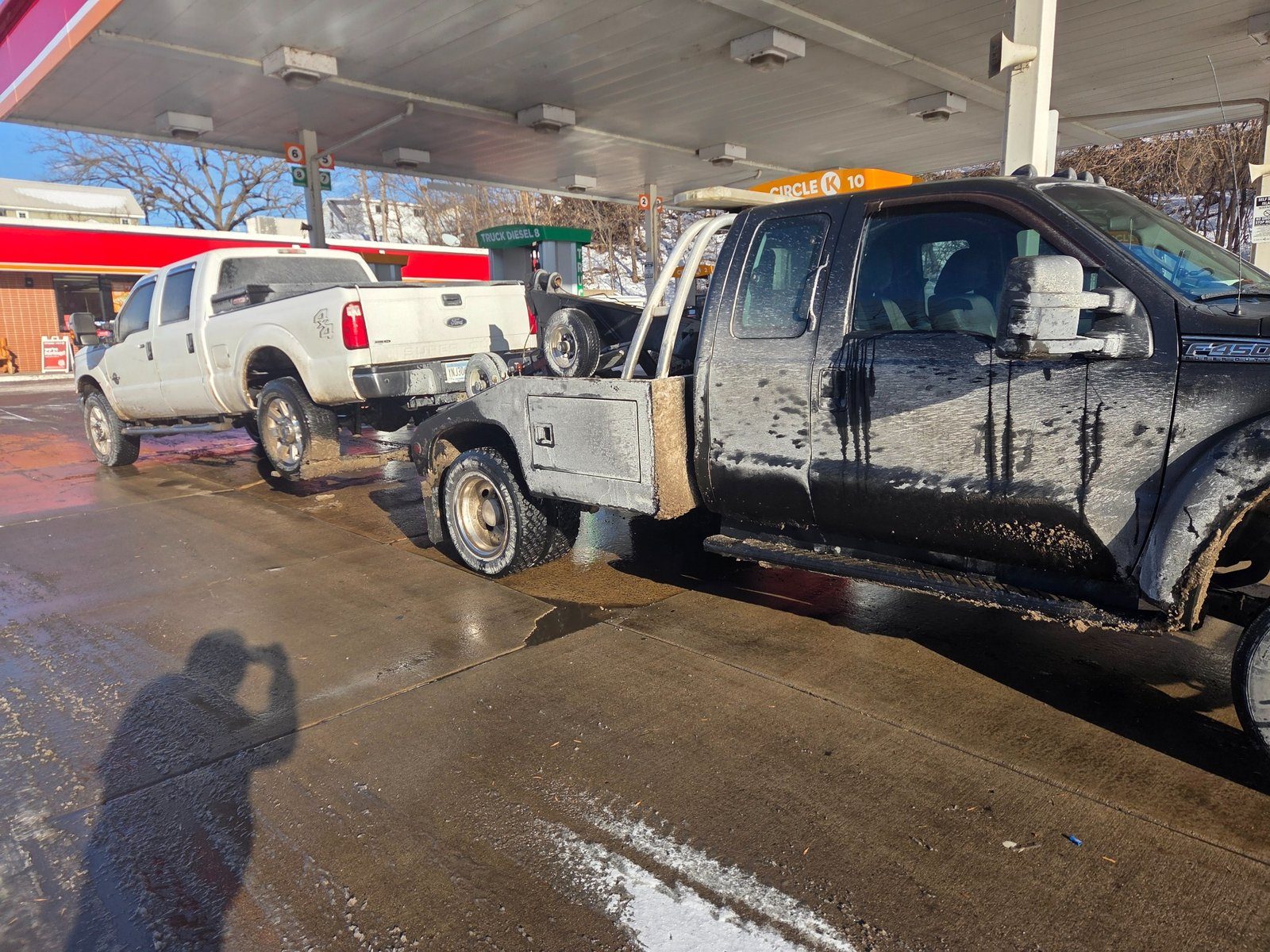 Pickup truck being towed by wheel lift at a gas station